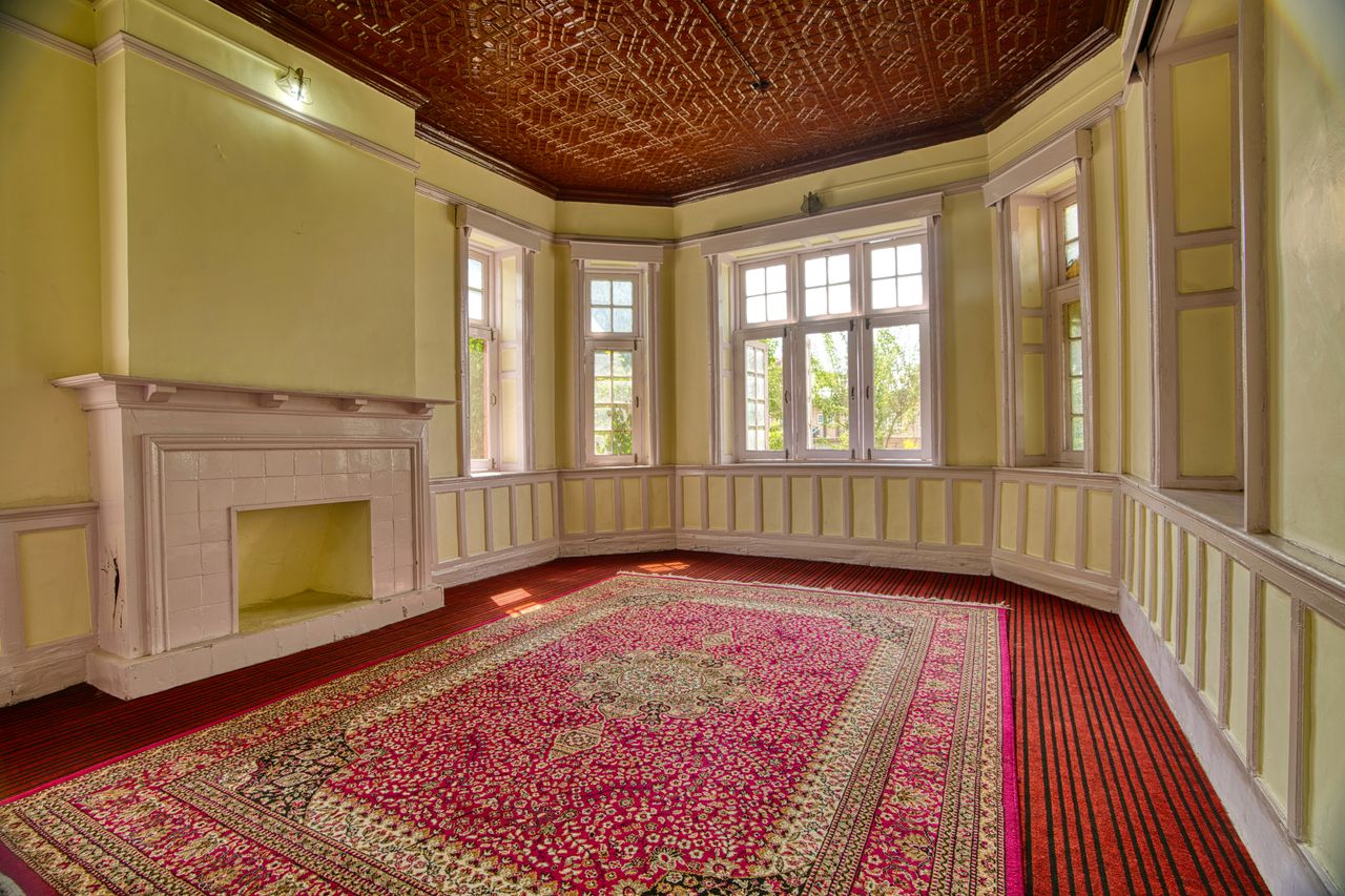 Menu A spacious, elegant room with large windows, fireplace, and vibrant carpet in Jammu and Kashmir.
